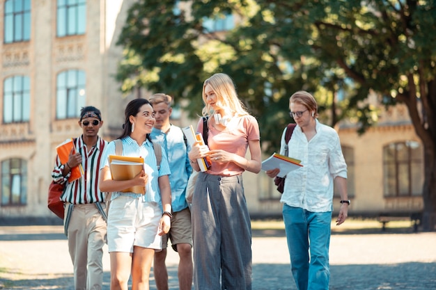 Gruppe freundlicher Studenten, die ihre Bücher halten und reden