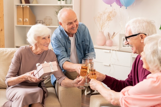 Gruppe fröhlicher älterer Freunde, die mit Champagner klirren, während sie Toast machen