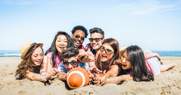 Gruppe gemischtrassiger, glücklicher Freunde, die Spaß daran haben, Sport-Strandspiele zu spielen