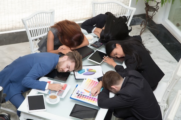 Gruppe Geschäftsleute, die im Konferenzsaal am Schreibtisch mit Abschluss stillstehend stillstehen