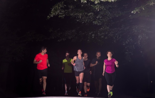 Foto gruppe gesunde leute, die im stadtpark, läufer rütteln, team am nachttraining