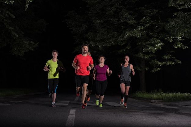 Gruppe gesunde Leute, die im Stadtpark, Läufer rütteln, team am Nachttraining