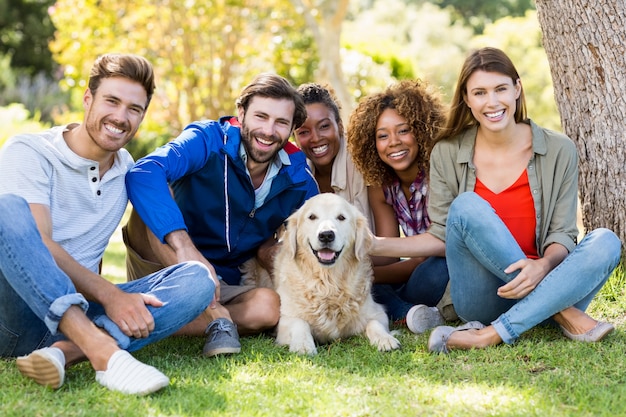 Gruppe glückliche Freunde, die zusammen mit dem Hund sitzen