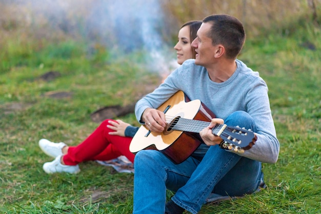 Gruppe glückliche Freunde mit der Gitarre, Spaß im Freien, nahe Feuer und touristischem Zelt habend. Camping Spaß glückliche Familie