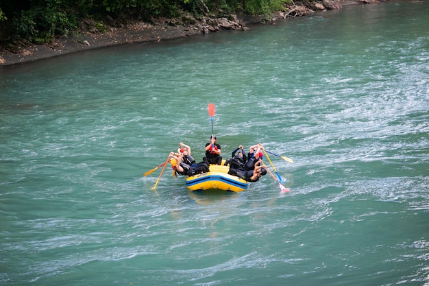 Gruppe glückliche Leute mit dem Führer Whitewater, der auf Fluss flößt und rudert.