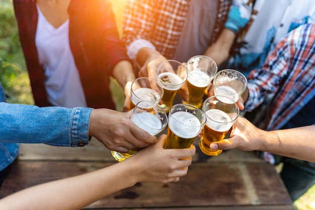 Gruppe glücklicher Freunde, die gesunden Lebensstil leben und sich entspannen, mit Bier jubeln und Bier trinken