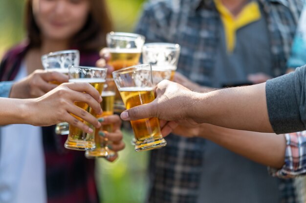 Gruppe glücklicher Freunde, die gesunden Lebensstil leben und sich entspannen, mit Bier jubeln und Bier trinken