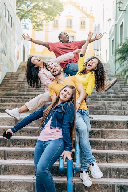 Gruppe glücklicher junger Freunde, die sich amüsieren, auf dem Geländer einer Treppe im Stadtzentrum zu sitzen