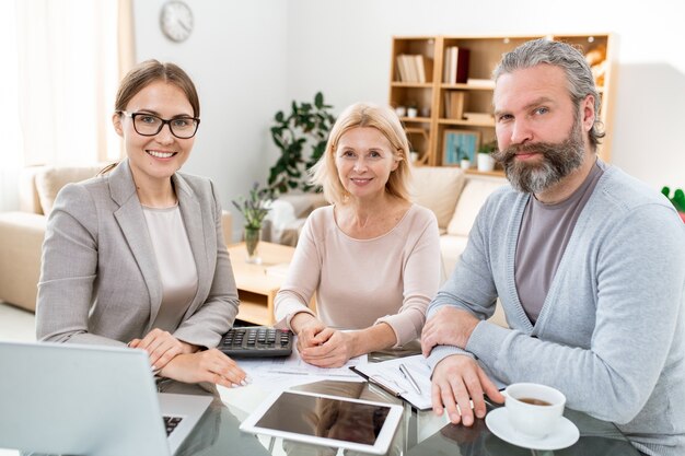 Gruppe glücklicher junger und reifer Kollegen, die am Arbeitsplatz sitzen