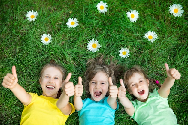 Foto gruppe glücklicher kinder, die im freien spielen, kinder, die spaß im frühling haben, parkfreunde, die auf gras liegen lying