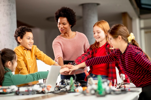 Gruppe glücklicher Kinder mit ihrer afroamerikanischen Lehrerin für Naturwissenschaften