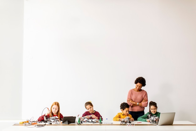 Gruppe glücklicher Kinder mit ihrer afroamerikanischen Lehrerin für Naturwissenschaften