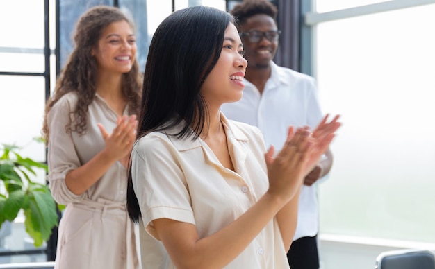 Gruppe glücklicher Mitarbeiter, die im Büro stehen und applaudieren