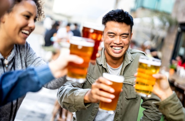 Gruppe glücklicher multikultureller junger Leute, die Bier im Brauerei-Bar-Restaurant trinken und anstoßen