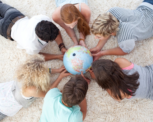 Gruppe Jugendliche auf dem Boden eine terrestrische Welt überprüfend