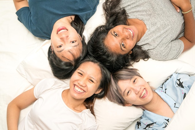 Gruppe junge Frauen, die glücklich und lächelnd im Bett liegen, Draufsicht