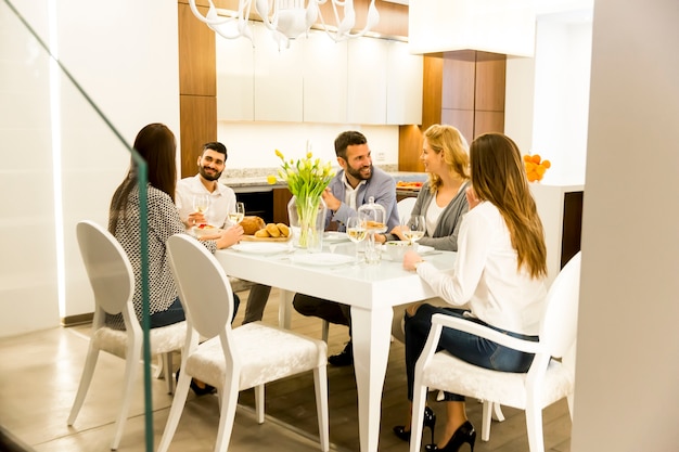 Gruppe junge Freunde, die zu Hause zu Abend essen und mit Weißwein rösten