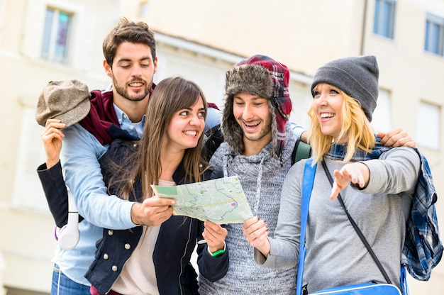 Foto gruppe junge hippie-touristenfreunde, die mit stadtplan in der alten stadt zujubeln