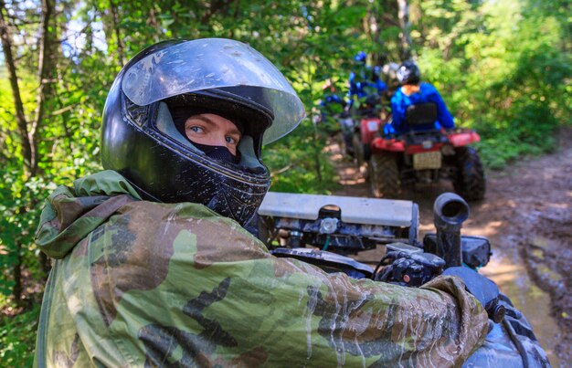 Gruppe junge Leute, die ATV auf Sandbahn reiten