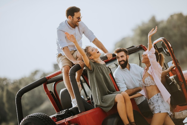 Gruppe junge Leute, die den Spaß mit dem Auto im Freien am heißen Sommertag haben