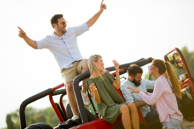 Gruppe junge Leute, die den Spaß mit dem Auto im Freien am heißen Sommertag haben