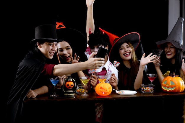 Gruppe junger Asiaten im Kostüm feiern Halloween-Party und Selfie auf schwarzem Hintergrund. Gang von Teenager-Asiaten im Cosplay Halloween. Kostümgeist, das Böse der Gruppe Teen Thai mit Spaß.