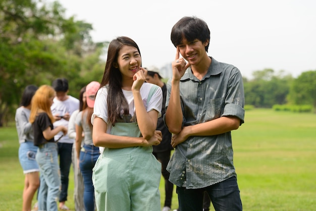 Gruppe junger asiatischer Freunde, die zusammen im Park draußen hängen und sich entspannen