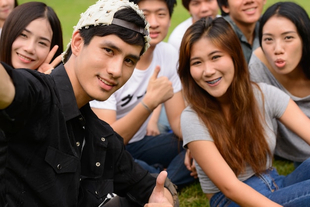 Gruppe junger asiatischer Freunde, die zusammen im Park draußen hängen und sich entspannen