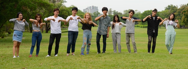 Gruppe junger asiatischer Freunde, die zusammen im Park draußen hängen und sich entspannen