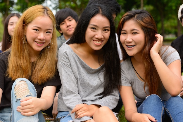 Gruppe junger asiatischer Freunde, die zusammen im Park draußen hängen und sich entspannen