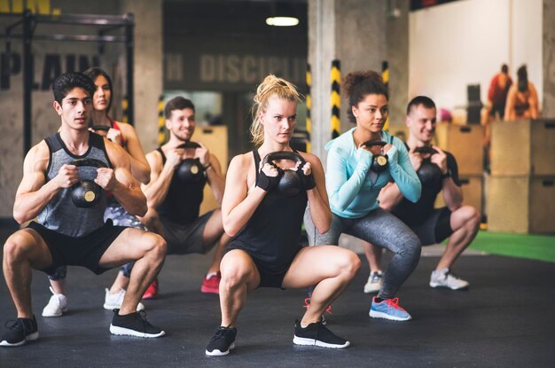 Gruppe junger fitter Menschen, die Kettlebells im Fitnessstudio heben