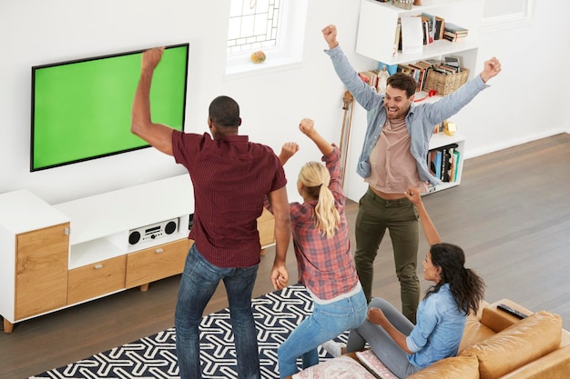 Gruppe junger Freunde, die im Fernsehen Sport gucken und jubeln