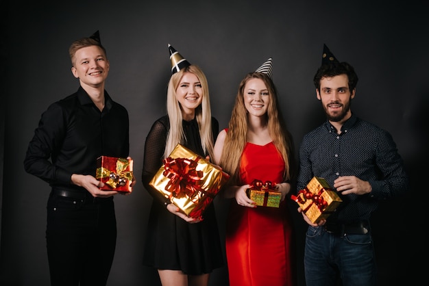 Gruppe junger Freunde, die mit festlichen Geschenkboxen in der Hand posieren