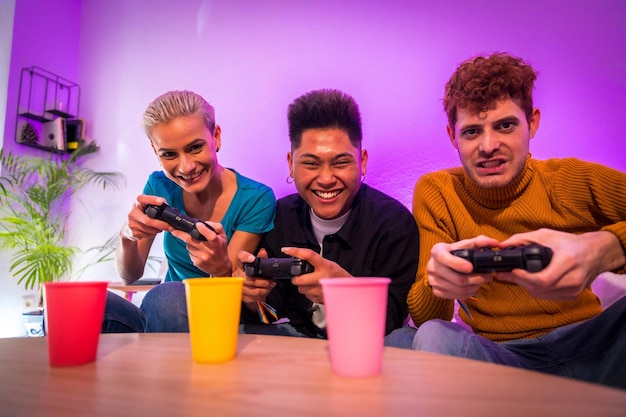 Gruppe junger Freunde, die zusammen Videospiele auf dem Sofa zu Hause spielen, lächelnde junge Millennials