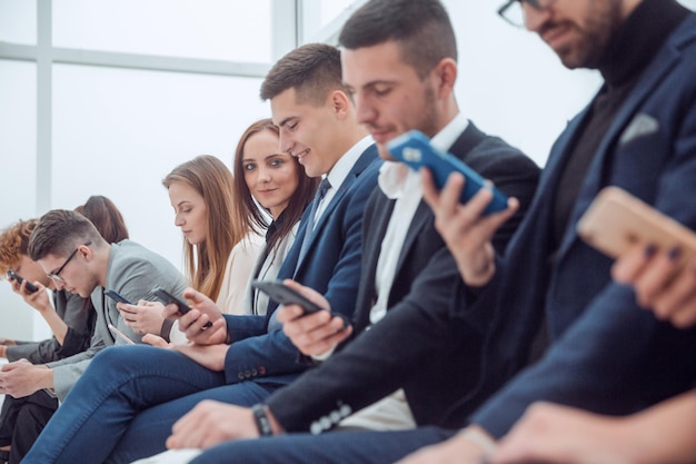 Gruppe junger Geschäftsleute, die auf ihre Smartphone-Bildschirme schauen