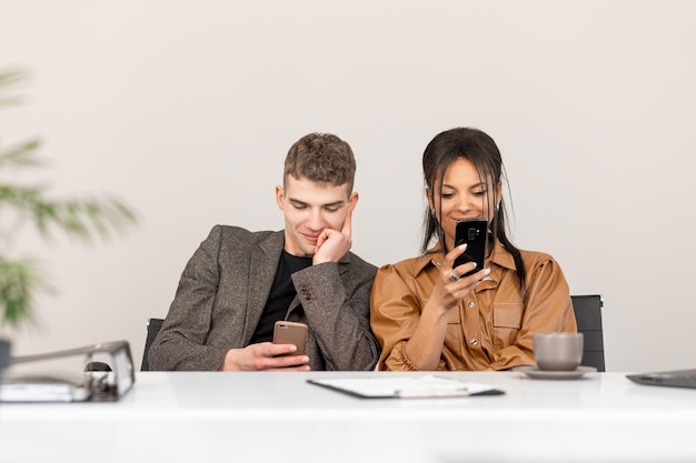 Gruppe junger Geschäftsleute, die im Büro mit Telefon in den Händen arbeiten