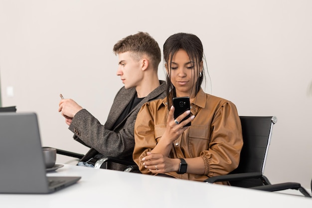 Gruppe junger Geschäftsleute, die im Büro mit Telefon in den Händen arbeiten