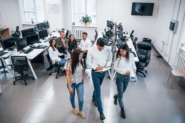 Gruppe junger Geschäftsleute, die im Büro stehen und sitzen und arbeiten.