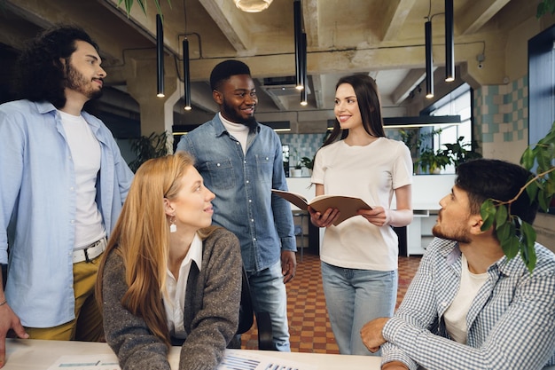 Gruppe junger Geschäftsleute, die während des Treffens im Büro Dokumente besprechen