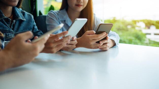 Gruppe junger Leute, die beim Zusammensitzen Handy benutzen und anschauen