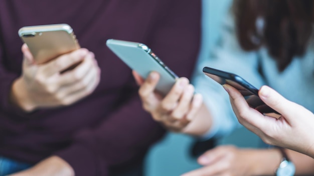 Gruppe junger Leute, die beim Zusammensitzen Handy benutzen und anschauen