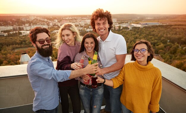 Gruppe junger Leute, die Bier trinken und zusammen auf dem Dach entspannen