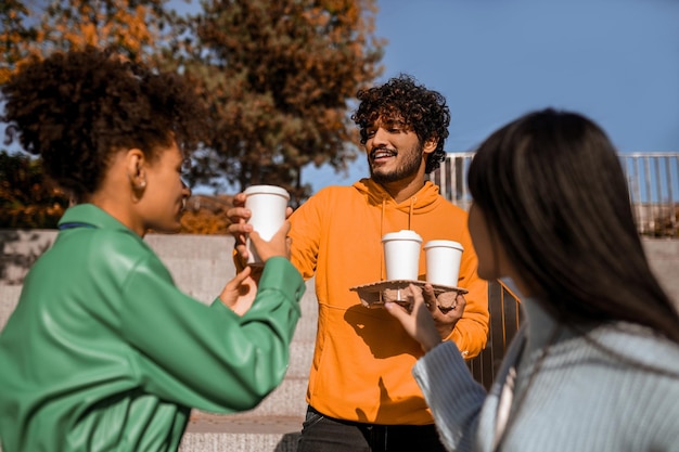 Gruppe junger Leute, die draußen Kaffee trinken und sich unterhalten