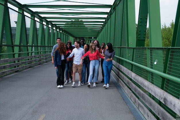 Gruppe junger Leute, die durch eine Brücke im Freien gehen