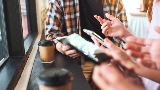 Foto gruppe junger leute, die ihre mobiltelefone halten und benutzen, während sie zusammensitzen und reden