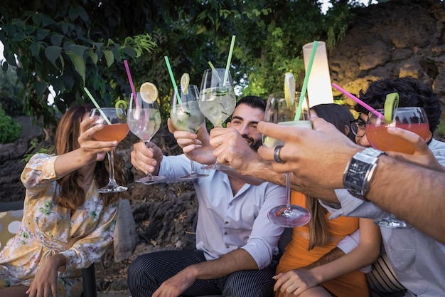 Gruppe junger Leute, die sich auf dem Terrassengarten zu einer Cocktailparty versammeln und die Gläser heben