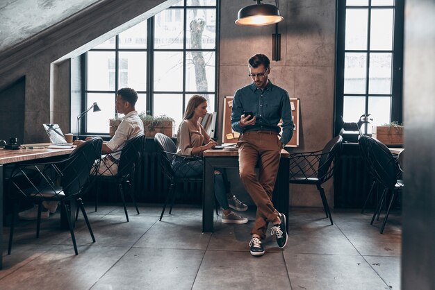 Gruppe junger Menschen in Smart Casual Wear mit modernen Technologien