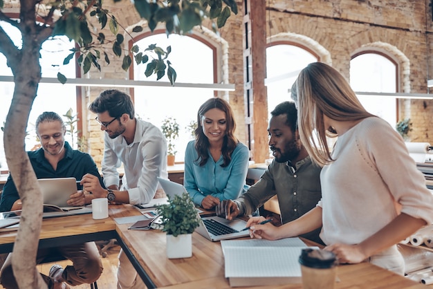 Gruppe junger moderner Menschen in smarter Freizeitkleidung, die Geschäftsideen bei der Arbeit im Büro sprechen