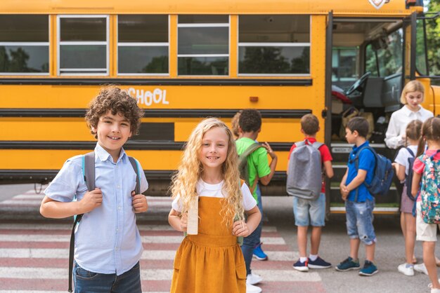 Gruppe junger Schüler, die die Grundschule in einem gelben Schulbus besuchen - Grundschulkinder, die Spaß haben
