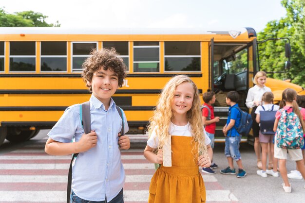 Gruppe junger Schüler, die die Grundschule in einem gelben Schulbus besuchen - Grundschulkinder, die Spaß haben